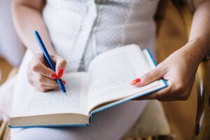 crop-woman-taking-notes-book-min